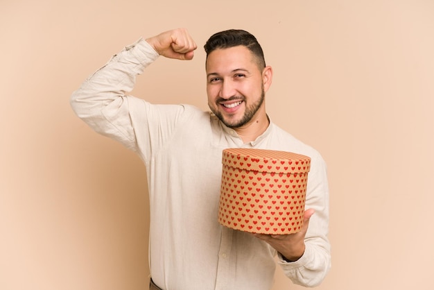 Hombre latino adulto sosteniendo un regalo del día de san valentín aislado