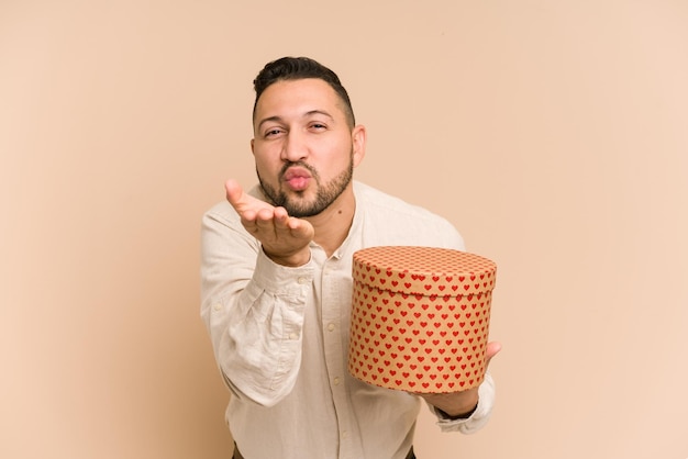 Hombre latino adulto sosteniendo un regalo del día de san valentín aislado