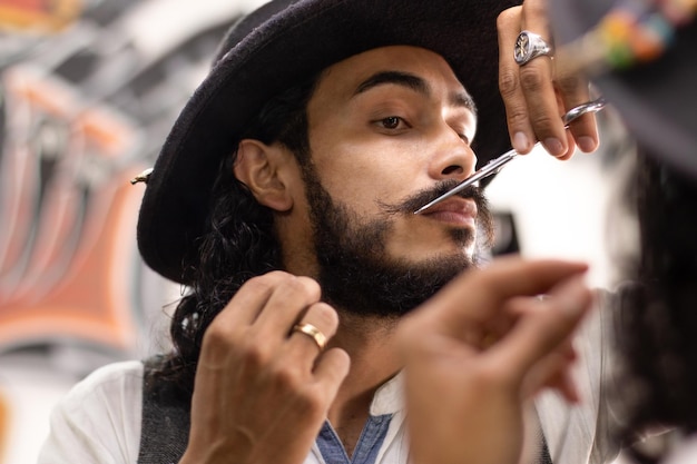Hombre latino barbudo arreglando su bigote en un espejo Estilista arreglando su barba con tijeras