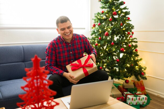 Hombre latino diciendo saludos con champán celebrando Navidad en una llamada de video
