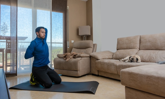 Hombre latino, haciendo ejercicio en su sala, hace abdominales, estiramientos y sentadillas