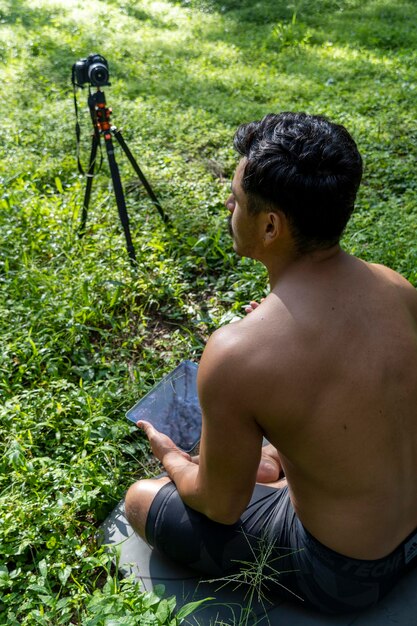 Hombre latino hispano dando clase mientras es grabado por una cámara sosteniendo un ipad o tableta en su mano méxico