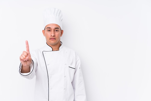 Hombre latino joven del cocinero aislado mostrando el número uno con el dedo.