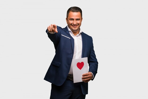 Hombre latino de mediana edad celebrando el día de San Valentín alegre y sonriente