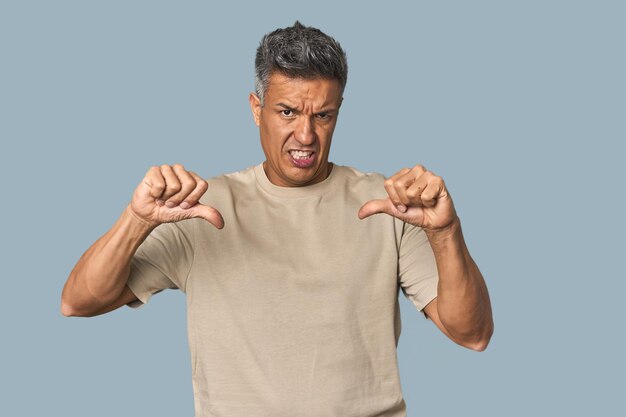 Foto hombre latino de mediana edad mostrando el pulgar hacia abajo y expresando aversión