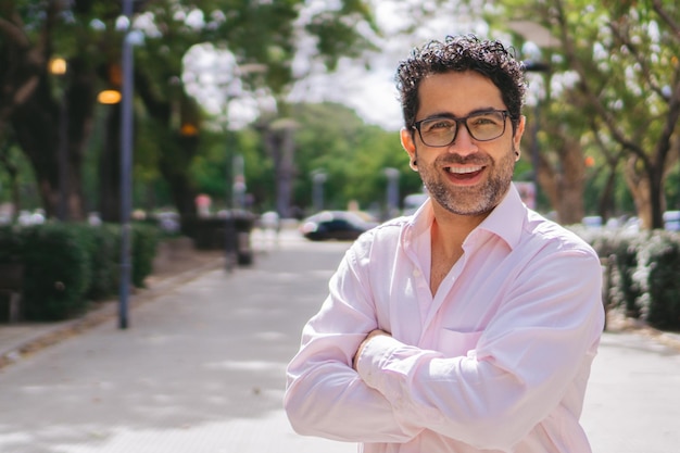 Hombre latino de mediana edad sonriendo con los brazos cruzados en la ciudad Copiar espacio