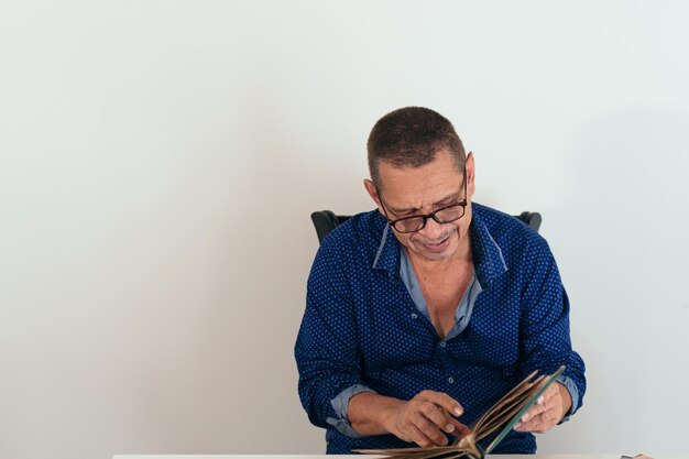 Hombre latino mirando un álbum de fotos sentado en su casa