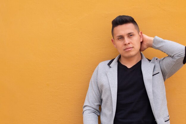 Foto hombre latino mirando lejos y usando una chaqueta gris aislada de fondo amarillo