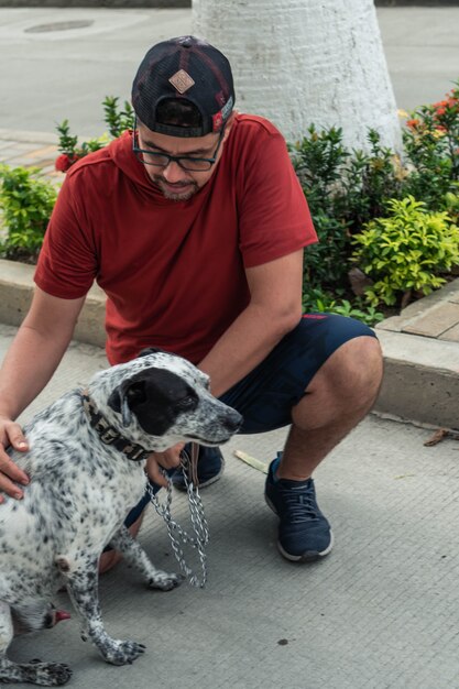 Hombre latino con perro en sus manos en el barrio