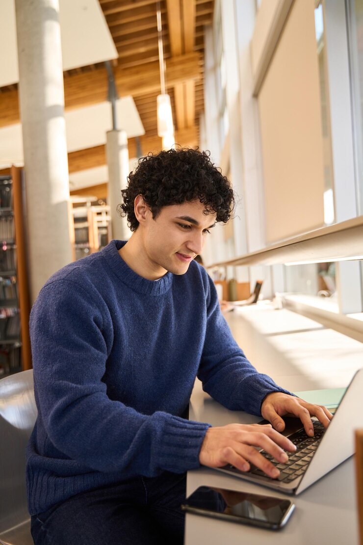 Hombre latino que usa una computadora portátil investigando en Internet escribiendo texto en el teclado comunicándose en línea