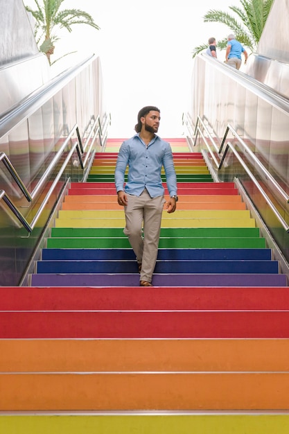 Hombre latino con rastas camina por escaleras coloridas