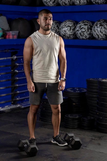 Hombre latino con ropa deportiva de pie en el gimnasio listo para hacer  ejercicio