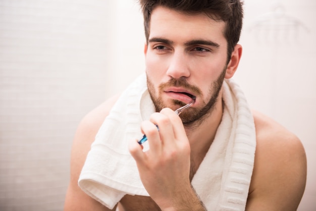 Un hombre se lava los dientes en el baño.