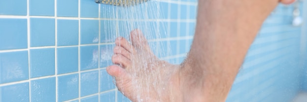 El hombre se lava el pie en la ducha de la piscina