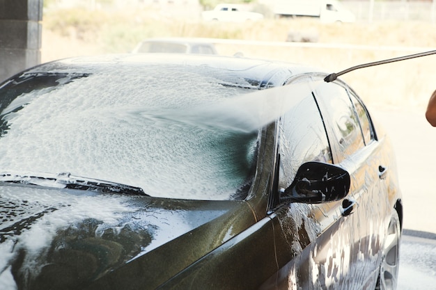 Un hombre lava su auto con agua.