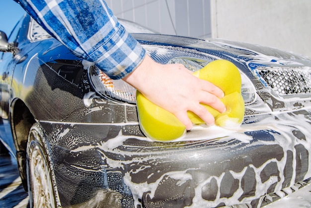 Hombre lavando auto con esponja amarilla concepto de lavado de autos