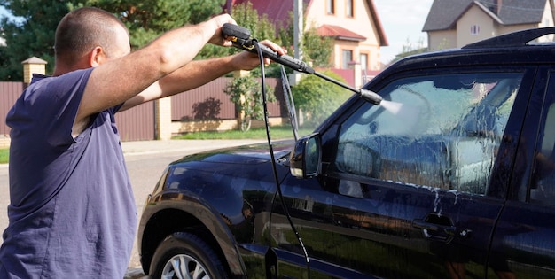 hombre lavando automóvil con lavado de automóvil lavado a presión lavado de champú esponjas y toallas de automóvil de microfibra