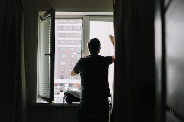Hombre lavando y limpiando ventanas en casa Tareas domésticas y limpieza higiene del hogar