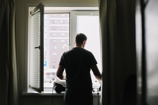 Hombre lavando y limpiando ventanas en casa Tareas domésticas y limpieza higiene del hogar