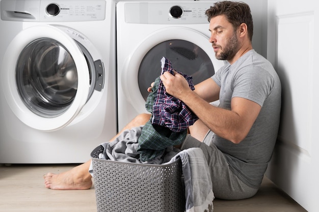 Hombre lavando ropa en casa cerca de lavadora esposo hombre lavando ropa en casa chico sexy lavadora puesta