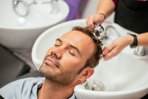 Hombre lavando su cabello en una barbería