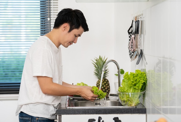 Hombre lavando verduras en el fregadero de la cocina en casa