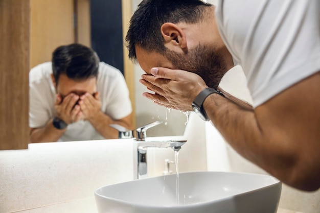 Un hombre lavándose la cara por la mañana.