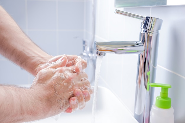 Foto hombre lavándose las manos con jabón en el baño