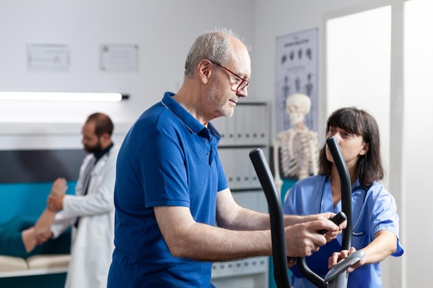 Foto hombre con lesión en la pierna haciendo fisioterapia para recuperación médica. paciente mayor con bicicleta para gimnasia y ejercicio deportivo para recuperarse con un especialista en ortopedia. entrenamiento de adultos mayores