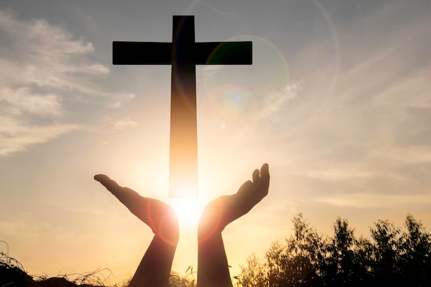 Un hombre levanta las manos y la cruza con la puesta de sol Ella es tan tranquila esperanza respeto crucifijo espiritual religión y paz Foto Cristiana y la idea del concepto de esperanza