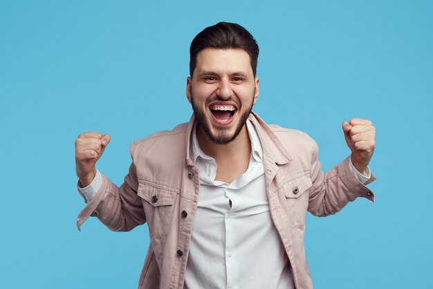 Foto el hombre levanta los puños con alegría celebra la victoria aislada sobre la pared azul