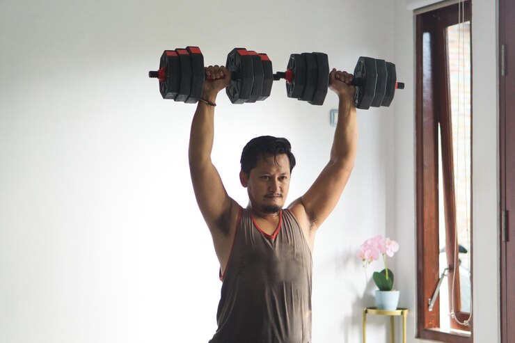 Hombre levantando pesas en el interior durante el entrenamiento en casa para el entrenamiento de fuerza