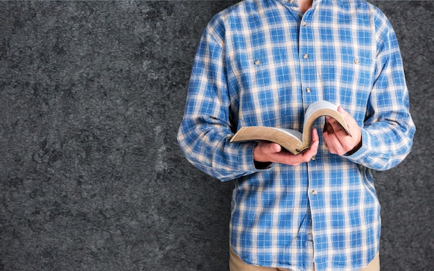 Hombre leyendo la Biblia sobre fondo azul.