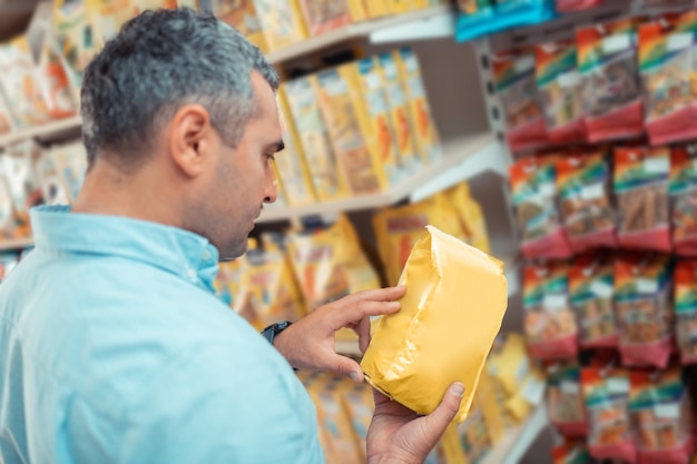 Hombre leyendo descripción eligiendo comida para gato