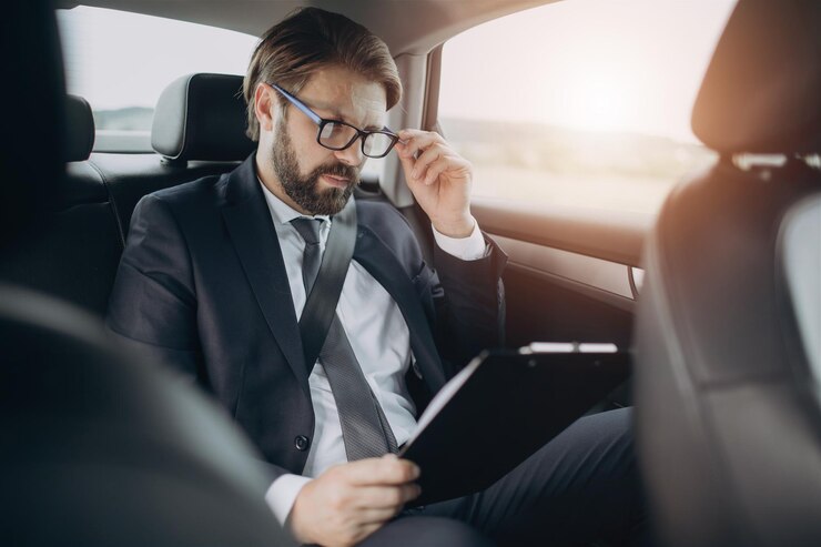 Hombre leyendo documentos mientras está sentado en el asiento trasero del coche