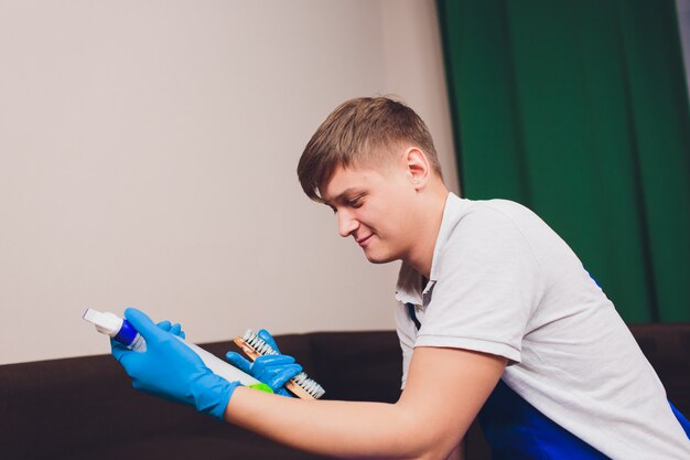 Hombre leyendo instrucciones en la botella de detergente de limpieza en casa con guantes protectores