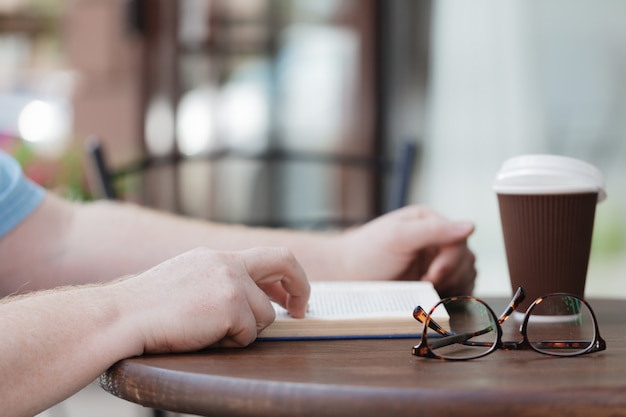 Foto hombre leyendo libro con café o té