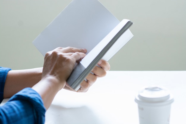 Hombre leyendo el libro con copia espacio para texto, taza de café en la mesa