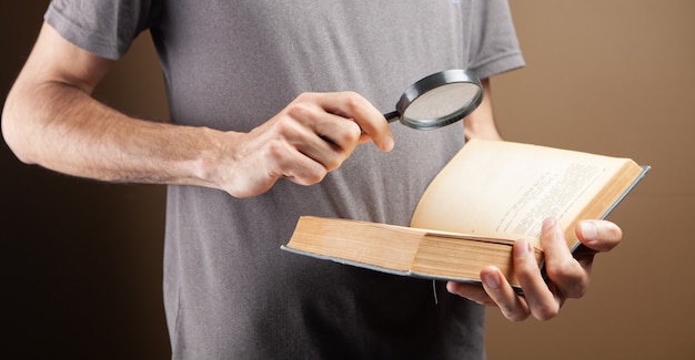 Hombre leyendo un libro con una lupa