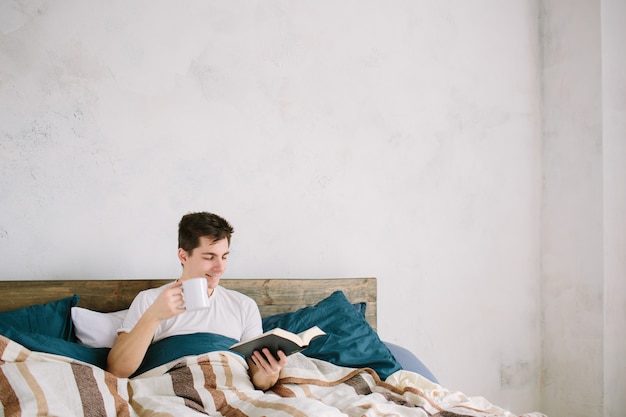 Hombre leyendo un libro en su cama en casa