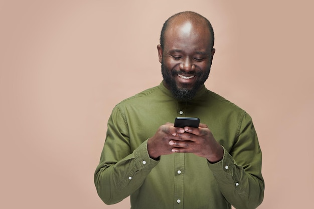 Hombre leyendo mensaje por teléfono y sonriendo