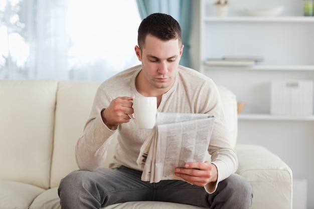 Hombre leyendo las noticias mientras bebe un café