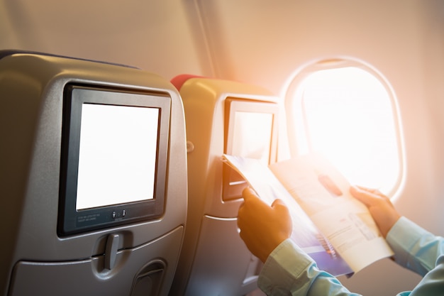 Hombre leyendo una revista en el asiento del avión con pantalla lcd individual
