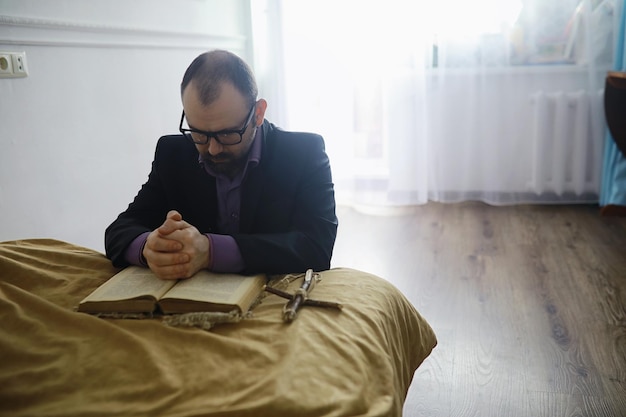 Hombre leyendo y rezando de la Santa Biblia cerca de la cama por la noche. Cristianos y concepto de estudio de la Biblia. Estudiar la Palabra de Dios en la iglesia.