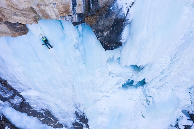 Foto el hombre está liderando en hielo escalada en hielo en cascada congelada vista aérea valle barskoon kirguistán