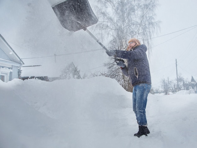 un hombre limpia la carretera de la nieve con una pala nevada por la mañana de invierno