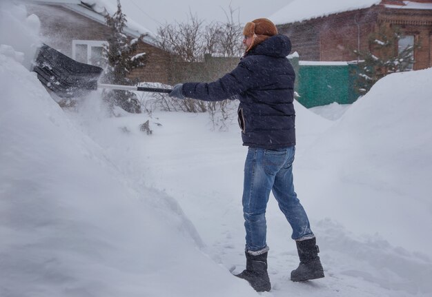 un hombre limpia la carretera de la nieve con una pala nevada por la mañana de invierno