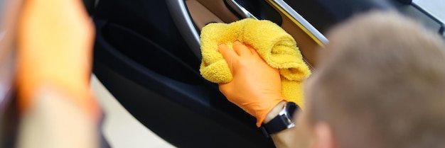 El hombre limpia el interior del coche con una toalla.