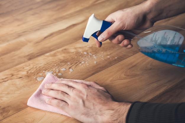 El hombre limpia la mesa con líquido y paño