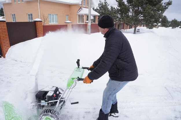 Un hombre limpia la nieve en invierno en el patio de la casa. Un hombre limpie la nieve con un soplador de nieve.